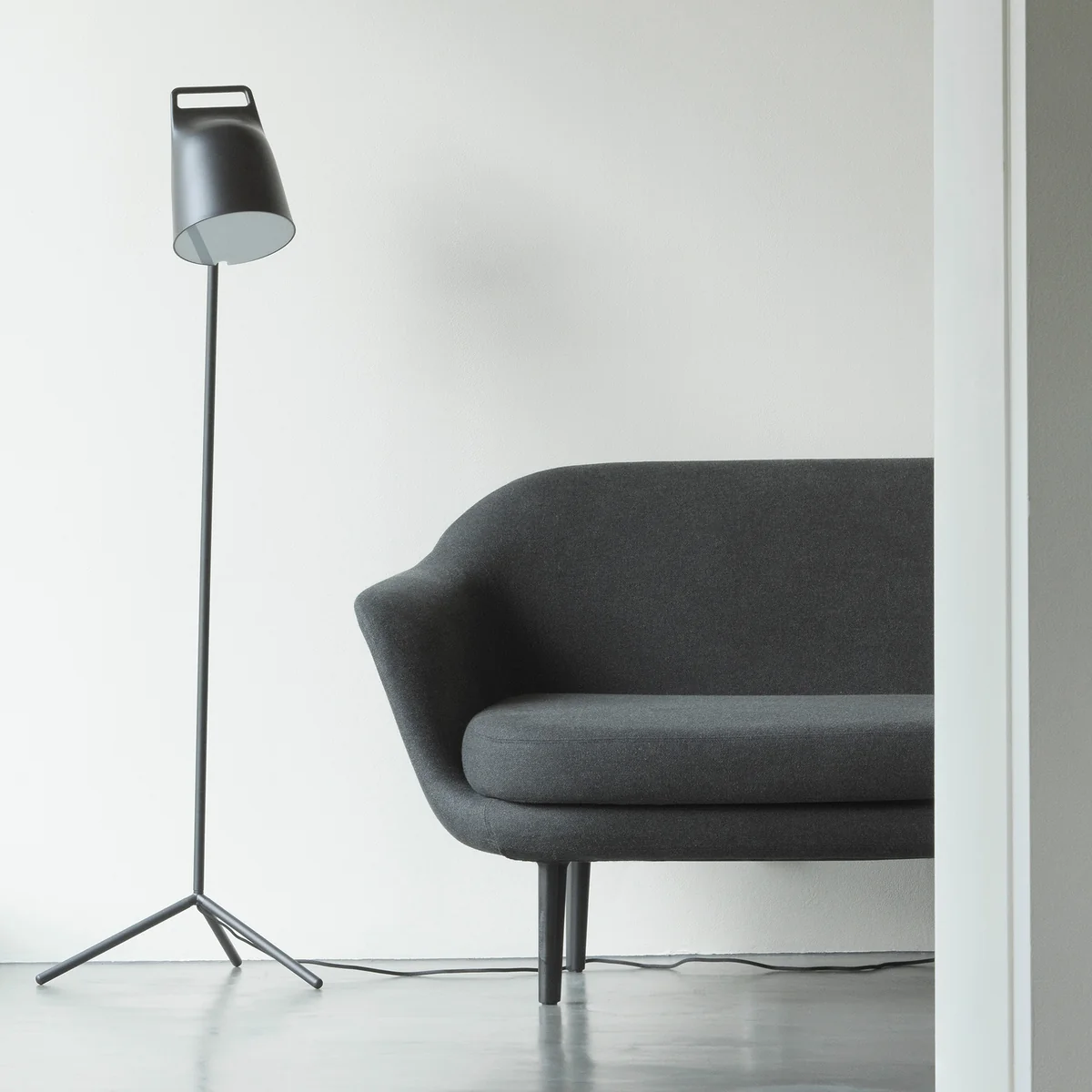 Le Stage Lampadaire LED de Normann Copenhagen à côté d'un canapé gris