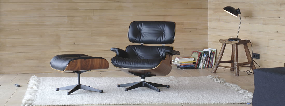 Le Vitra Eames Lounge Chair par Charles & Ray Eames avec un confort ultime et la plus haute qualité dans les matériaux et la finition. Le fauteuil en placage foncé et cuir noir est désormais également disponible en noyer/blanc.