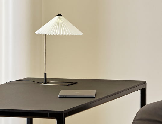 La lampe de table Matin LED de Hay dans la vue d'ambiance : La lampe de table avec son abat-jour plissé est particulièrement belle comme lampe de lecture à côté du lit.