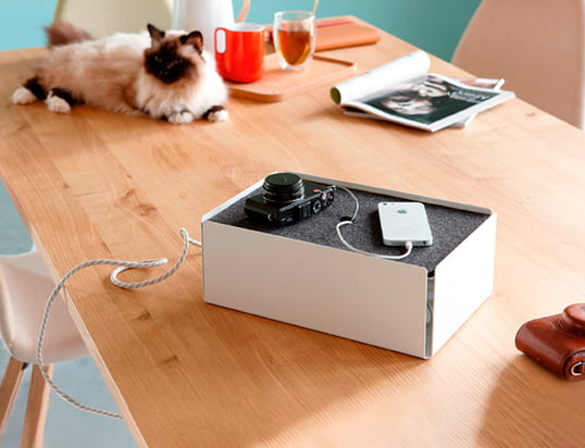 La boîte de charge de Konstantin Slawinski dans la vue d'ambiance : La boîte cache les câbles de recharge des iPhones, des appareils photo et d'autres appareils de manière élégante sur la table de cuisine.