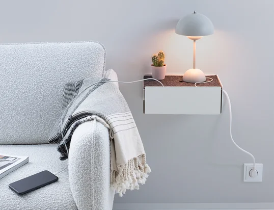 La boîte de charge de Konstantin Slawinski dans la vue d'ambiance : La boîte cache les câbles de recharge des iPhones, des appareils photo et d'autres appareils de manière élégante sur la table de cuisine.