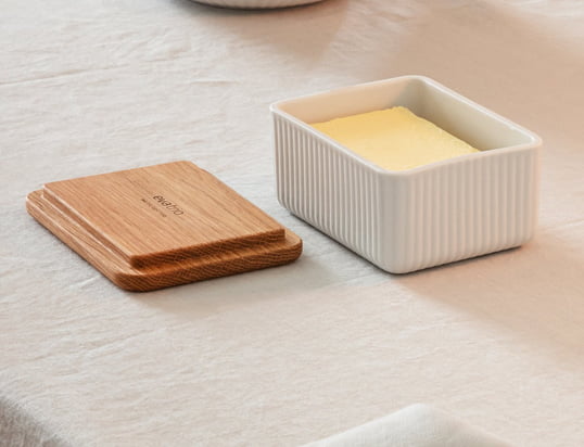 Le beurrier chic Legio Nova d'Eva Trio en chêne se compose d'un couvercle en bois de chêne et d'un bol en porcelaine fine avec un motif rainuré. Le morceau de beurre peut être conservé dans le bol en porcelaine et fermé par le couvercle en bois.
