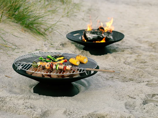 Le foyer Helios de Skagerak crée une atmosphère et une ambiance chaleureuses dans le jardin. Mais elle est aussi parfaite pour les grillades avec la grille en acier inoxydable qui l'accompagne.