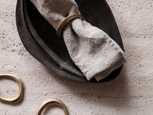 Représentation du produit Lifestyle des ronds de serviette décoratifs Flow en laiton dans un ensemble pratique de 4 et du plateau décoratif Forest en laiton noir de ferm Living.