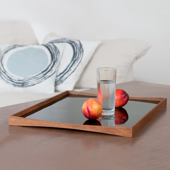 Le Tablett Turning Tray avec un verre à côté du canapé