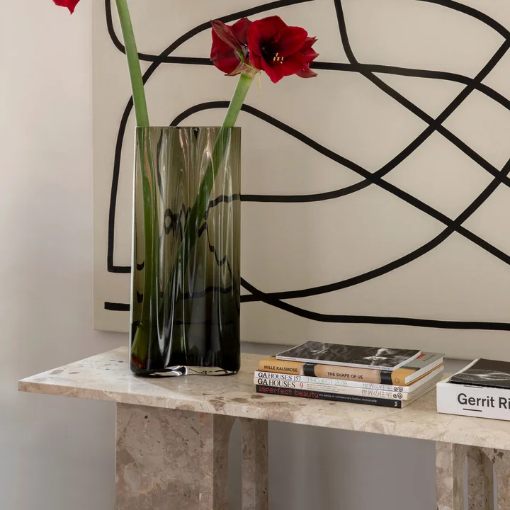 La table de salon Androgyne de Audo en combinaison avec une grande œuvre d'art au mur, un vase et des livres