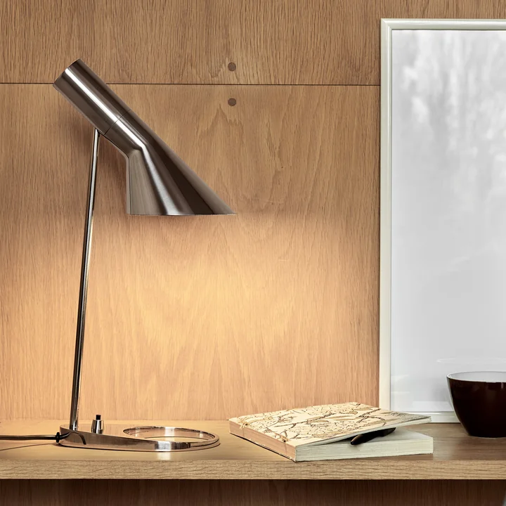 La lampe de table AJ de Louis Poulsen sur un bureau en bois