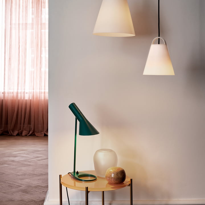 La lampe de table AJ de Louis Poulsen sur une table d'appoint en bois dans le couloir