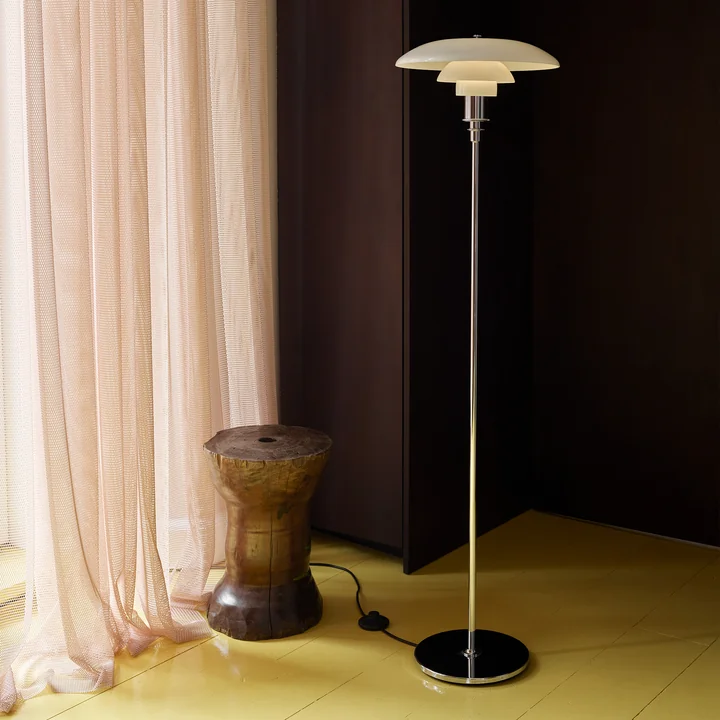Le lampadaire PH, chromé brillant de Louis Poulsen dans une chambre à coucher assombrie