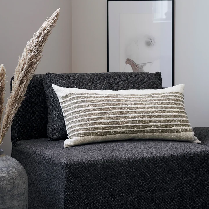 La taie d'oreiller Yarn, jaune moutarde de House Doctor sur un fauteuil foncé