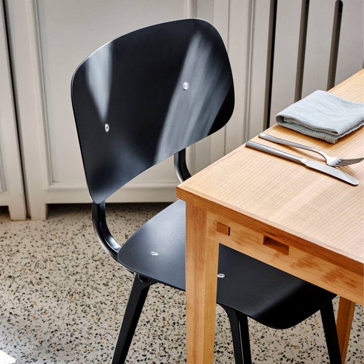 La chaise Revolt, noir / noir de Hay sur une table à manger en bois