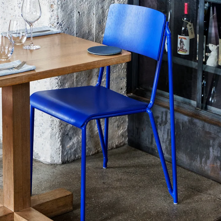 La chaise Petit Standard, ultra marine blue / ultra marine blue de HAY sur une table en bois dans la cave à vin