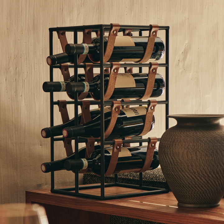 Le casier à vin Umanoff pour 8 bouteilles, acier noir (RAL 9005) / cuir brun de Audo sur un comptoir en bois