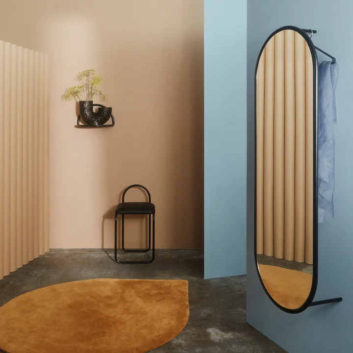 Le miroir mural Angui de AYTM sur un mur bleu dans la garde-robe