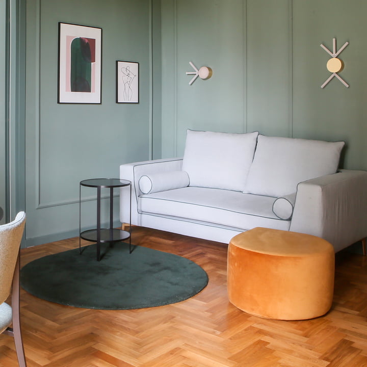 Le Stilla tapis AYTM du salon coloré avec ses murs verts et son parquet en bois