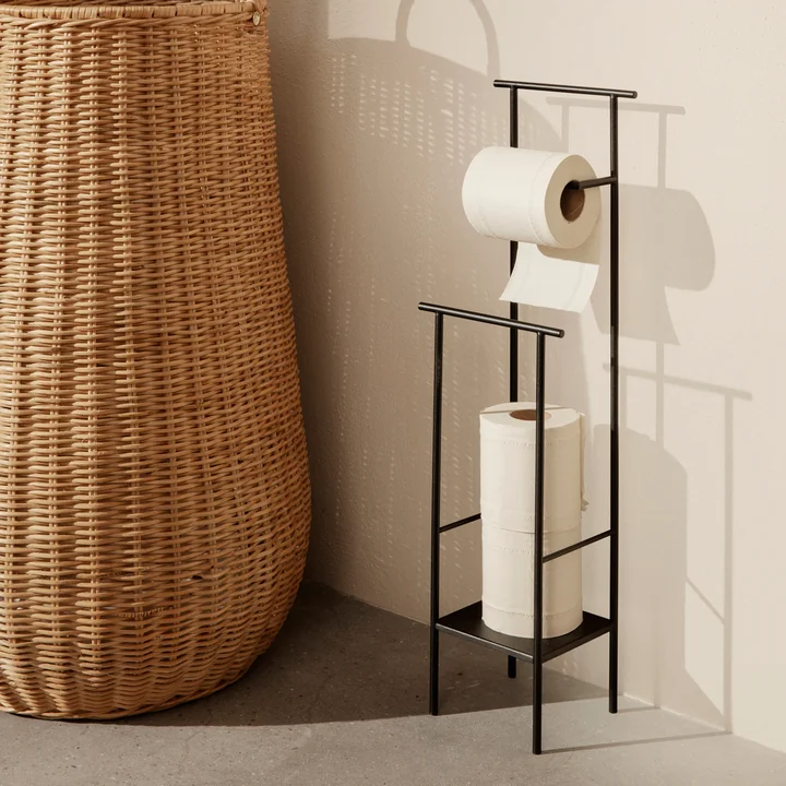 Le porte-papier toilette Dora de Ferm Living à côté d'un grand panier en rotin