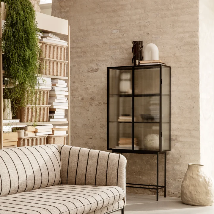 Le Haze Vitrine par ferm Vivre avec de nombreux vases d'art et livres sur un mur de pierre dans le salon