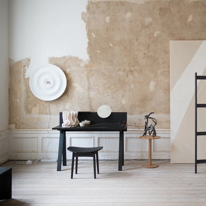 Le site Alma Applique et plafonnier de Wästberg en blanc dans un studio lumineux avec bureau et chaise noirs