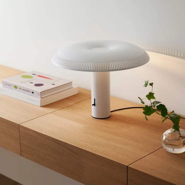 La lampe de table w203 Ilumina LED de Wästberg en blanc sur un banc en bois à côté de livres et de vases