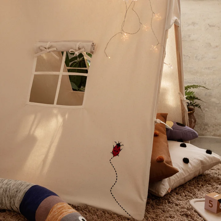 La tente de jeu de Ferm Living avec coussins et lumières de fées dans la chambre des enfants