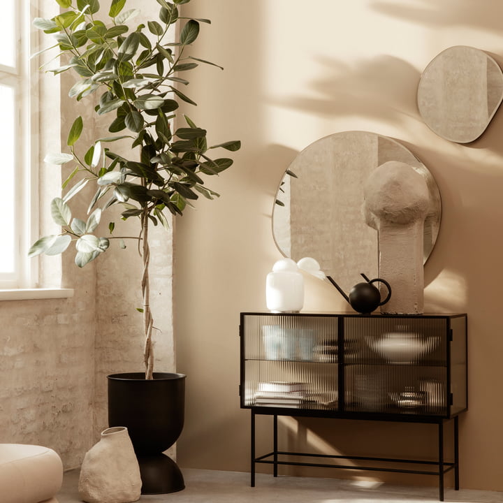 Le miroir Pond de ferm Living au-dessus d'un sideboard artistiquement décoré