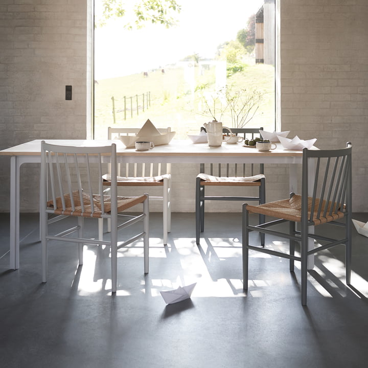 La chaise J80 de FDB Møbler dans ses différentes couleurs à une grande table de salle à manger blanche devant la fenêtre