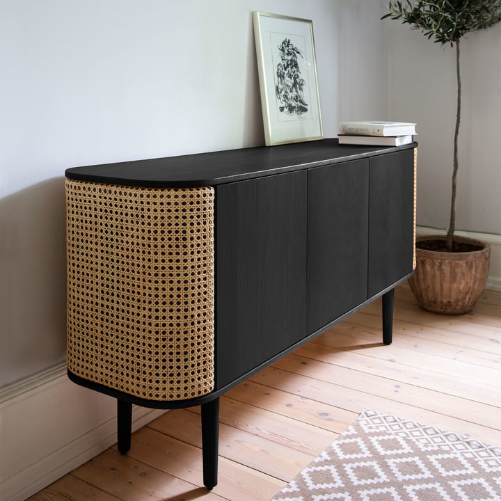 Le site Treasures Sideboard de Umage en noir / tressage viennois à côté d'une plante d'intérieur et d'images