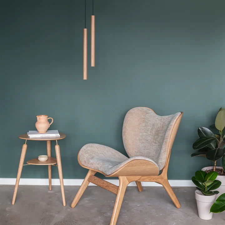 Le site Chimes Suspension LED en chêne au-dessus d'un fauteuil lounge et d'une table d'appoint en bois, le tout de Umage