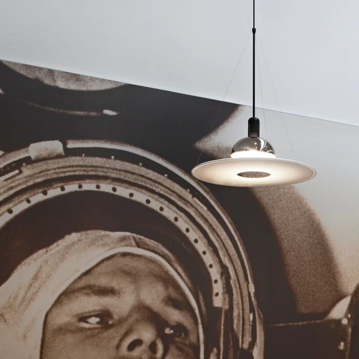 La lampe à suspension Frisbi de Flos en chrome devant une grande photo