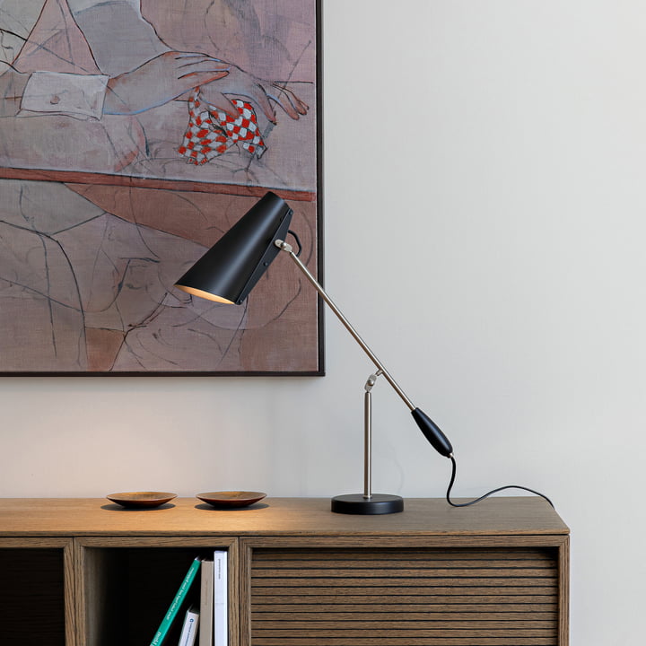 Le site Birdy lampe de table de Northern sur une commode en bois devant une œuvre d'art