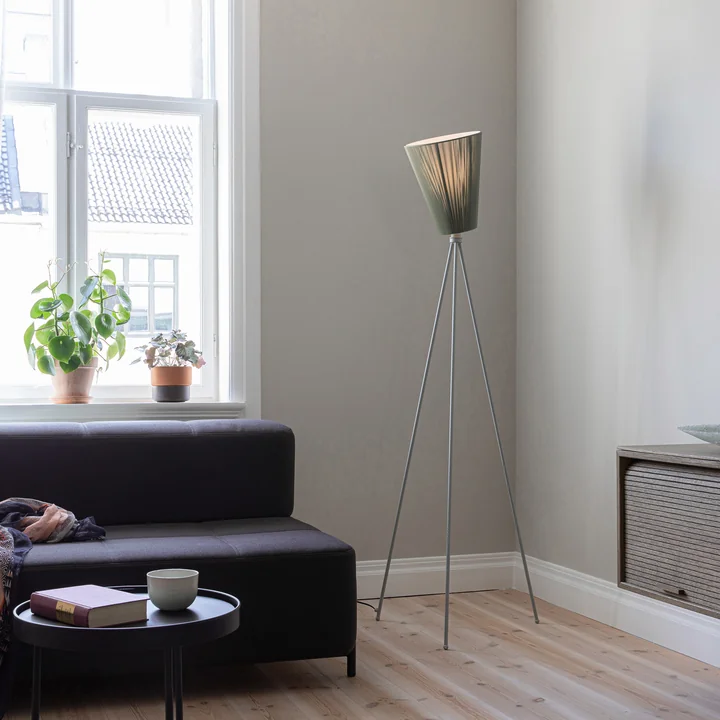 Le lampadaire Oslo Wood de Northern dans le salon à côté d'un canapé sombre