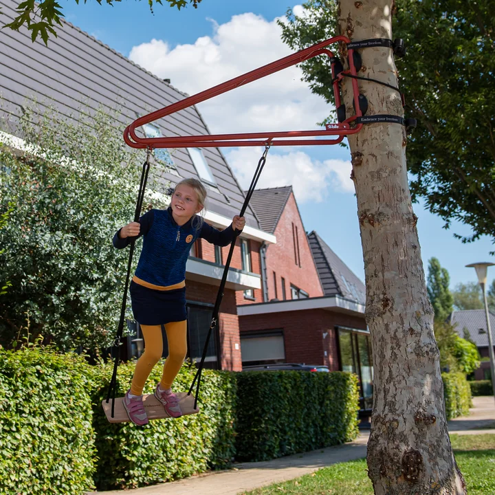 La balançoire Swing de Weltevree sur un arbre dans un quartier de maisons.