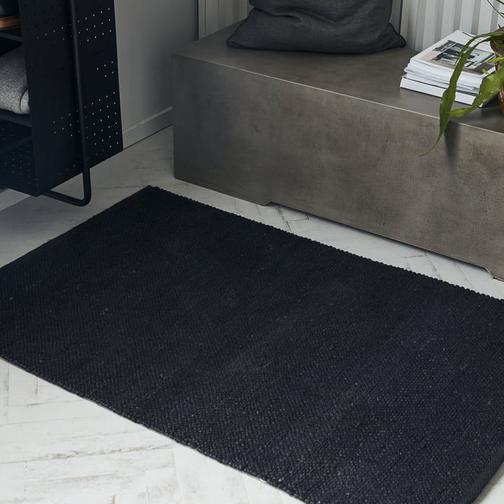 Le tapis noir Hempi de House Doctor devant un banc en béton