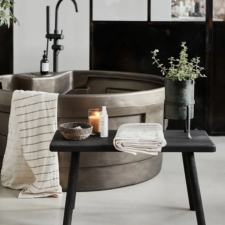 Le banc Nadi de House Doctor comme étagère à côté de la baignoire