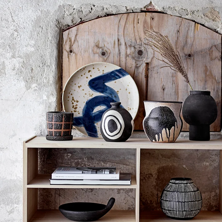 La plaque murale Oscar de Bloomingville sur un buffet en bois à côté de vases et d'objets décoratifs.