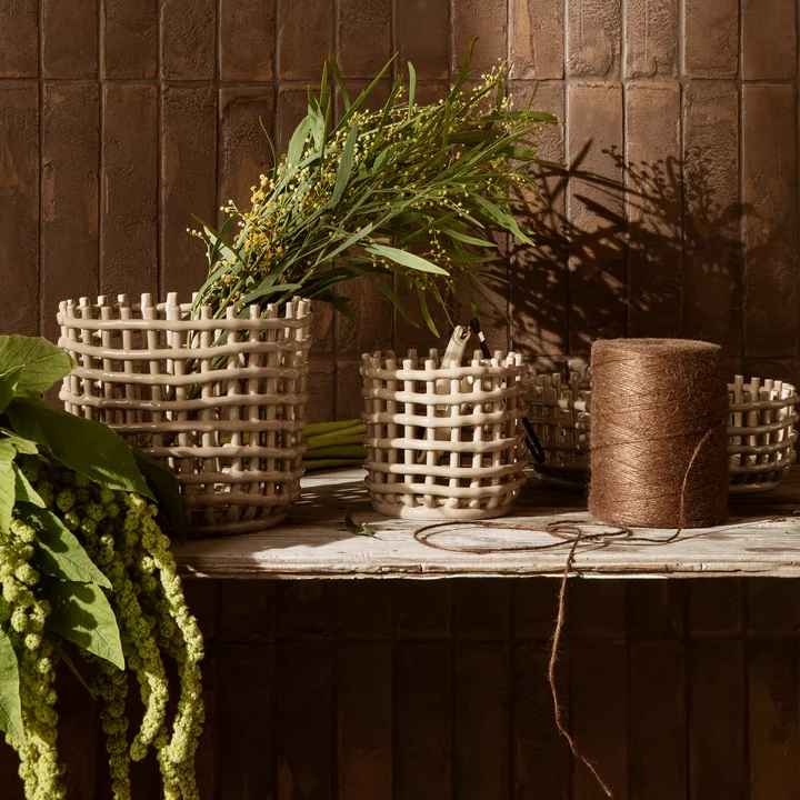 Les paniers en céramique de Ferm Living avec des plantes sur un banc en bois