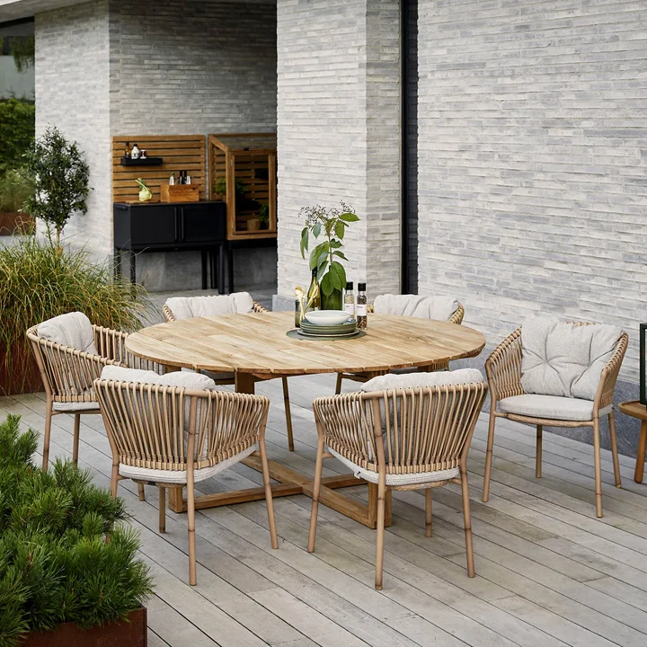 La chaise à accoudoirs Ocean Outdoor de Cane-line à la table de jardin