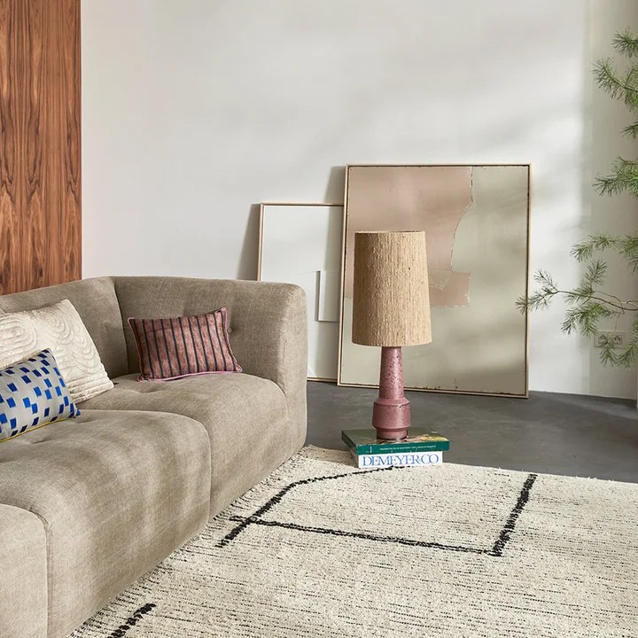 Le pied de la lampe de table Retro de HKLiving sur le sol, à côté du canapé.