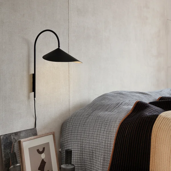 Arum Applique murale en noir de Ferm Living à côté du lit